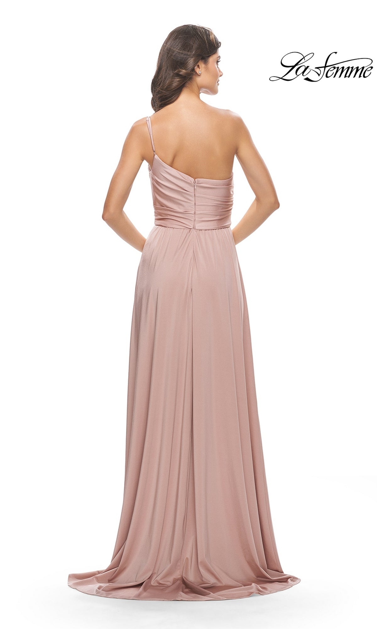 A woman faces away, wearing the One-Shoulder Long La Femme Formal Dress 31170 in blush pink. The gown features a ruched bodice and flowing skirt, making it a stunning choice for prom. The La Femme logo is visible in the upper right corner.